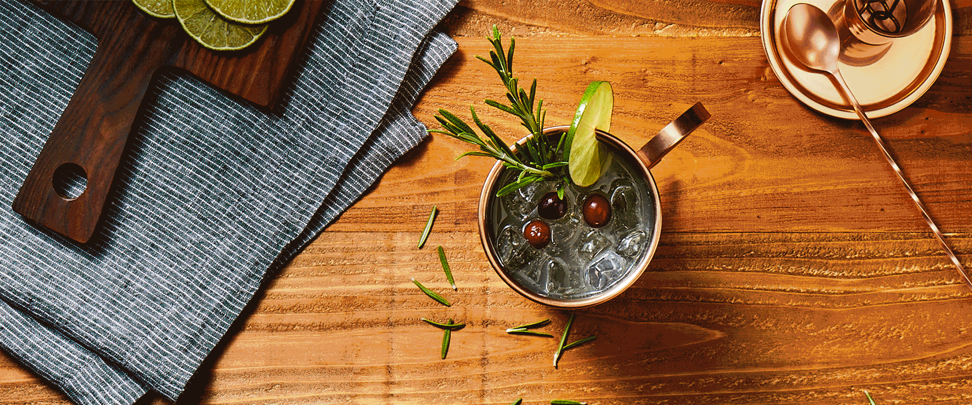 A copper mug with cherries and rosemary twigs made with cocktail mix.